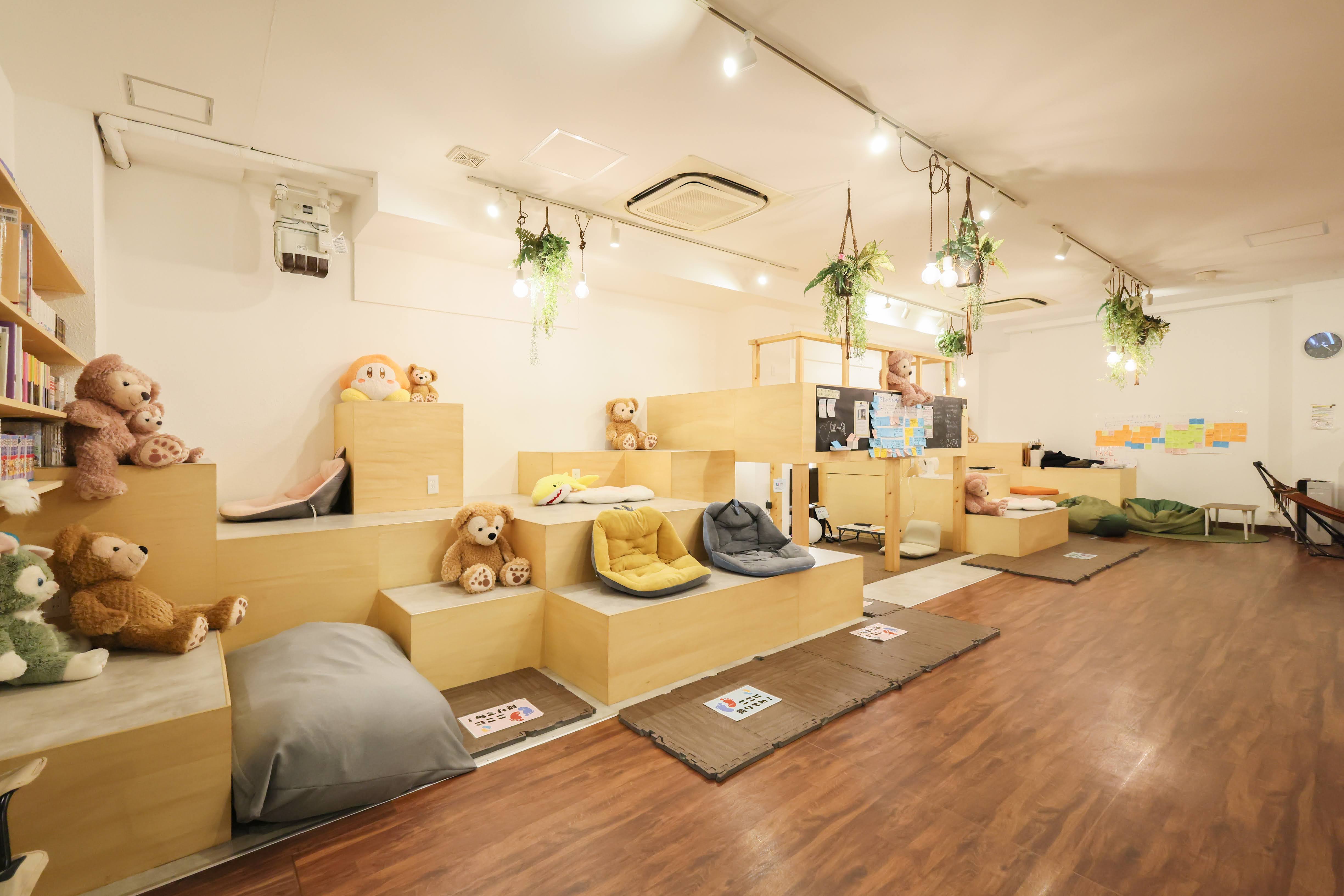 木のフロアに植物やぬいぐるみが置かれた、あたたかいユースセンターの内観